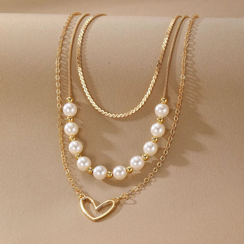 Vintage gold necklace with heart pendant on pearl chain showing adjustable length mechanism