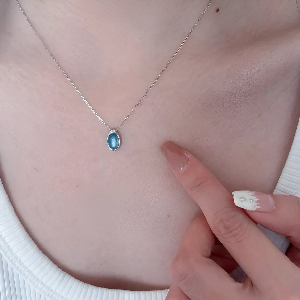 Navy blue water droplet necklace with geometric cross chain on white background