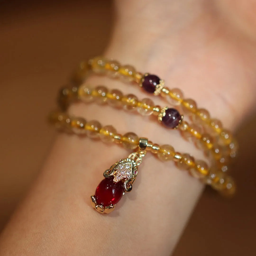 Handmade gold and ruby quartz bracelet with a chopstick charm on a wrist.
