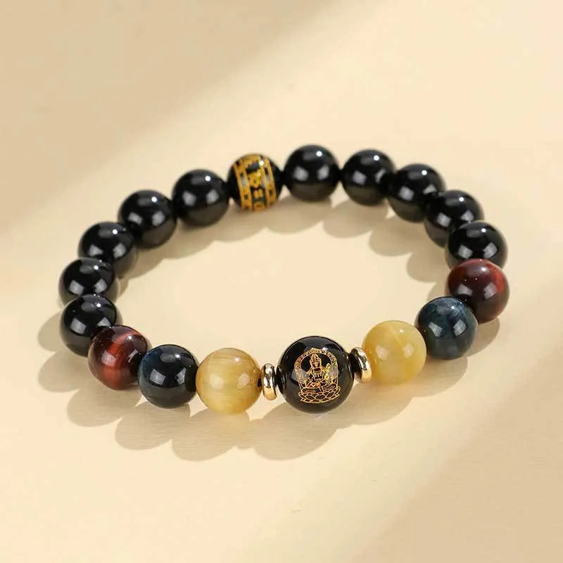 Black agate beaded bracelet with gold tiger eye accent and Chinese zodiac bodhisattva charm on neutral background
