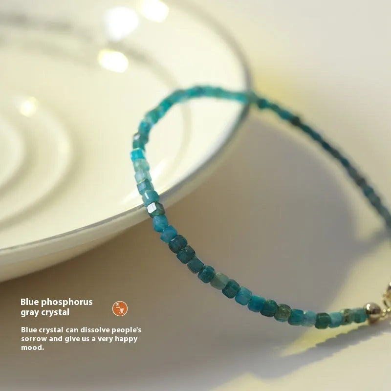 Natural blue apatite crystal bracelet with diamond-shaped beads, blue and grey colour, on a white background