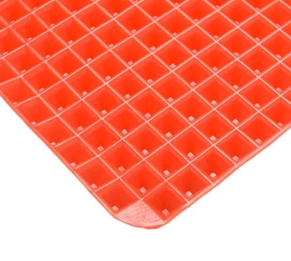 Red non-stick silicone pyramid cooking mat on a baking tray, showing grid pattern and 39.5 cm size