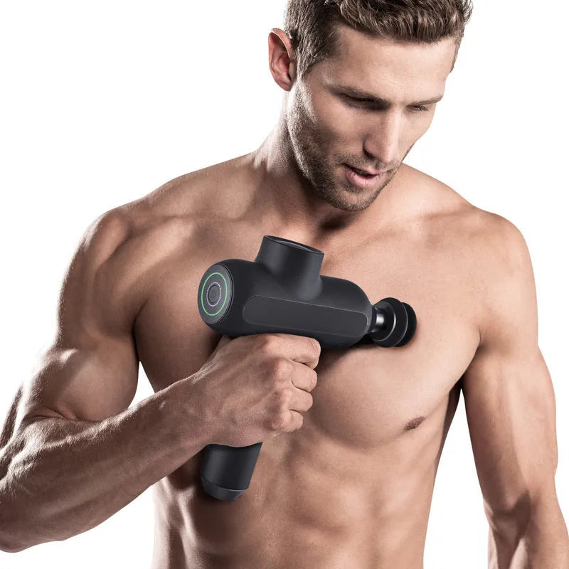 Black rechargeable muscle massager with six different coloured massage heads on a table.