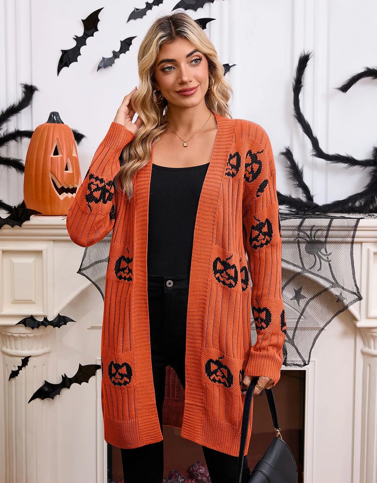 Women's black Halloween cardigan with jacquard-knitted orange pumpkin head pattern, shown as a straight-cut medium-length coat.