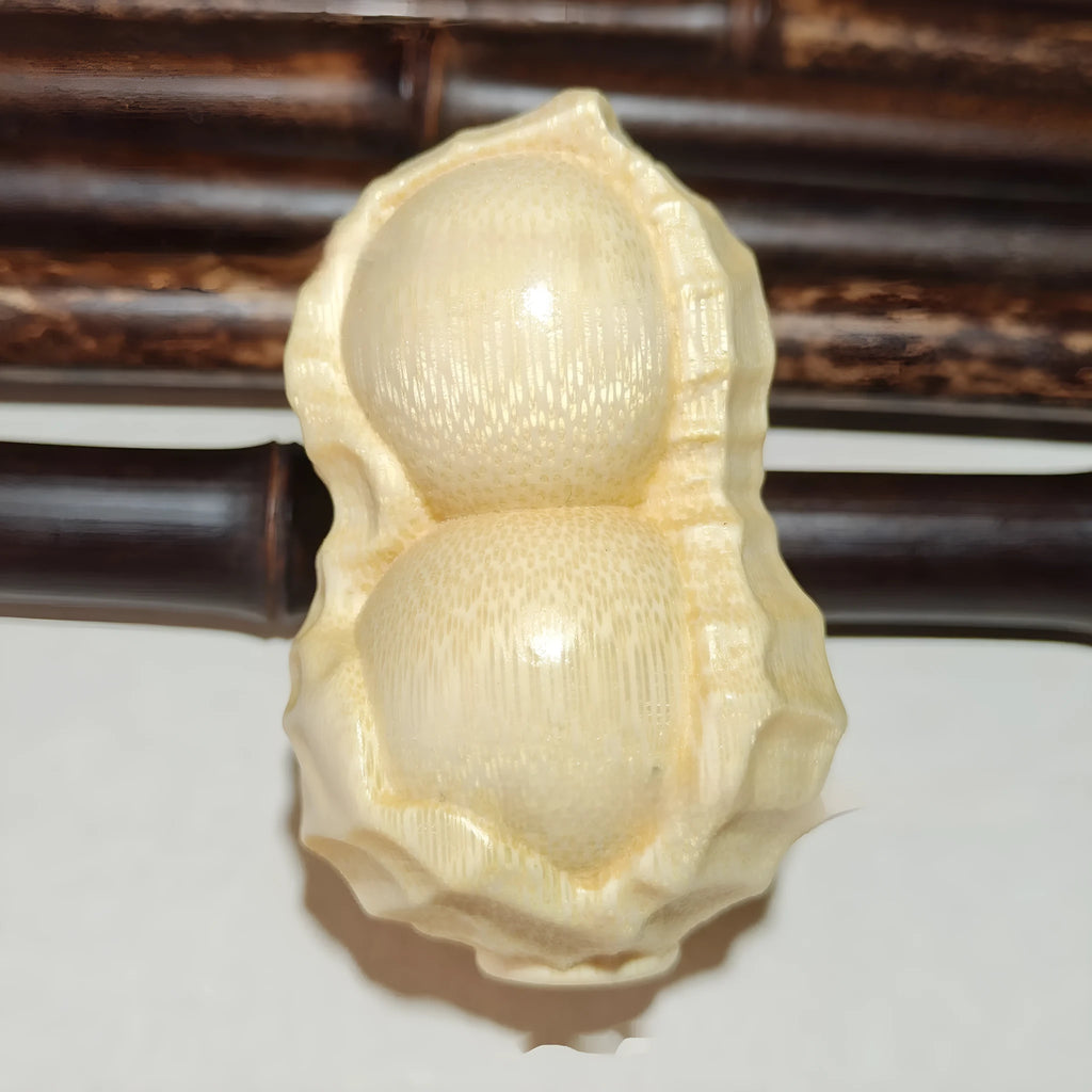 Solid natural bamboo ornament carved into a peanut shape on a wooden surface.