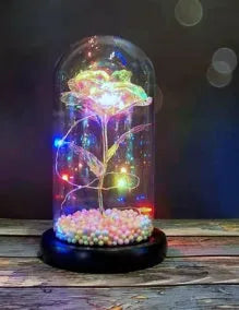Gold artificial rose inside glass dome with LED lights on black base for home display