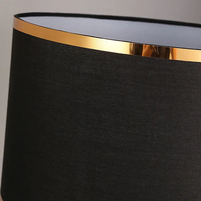 Simple bedroom table lamp with iron body and fabric shade in black finish on wooden desk