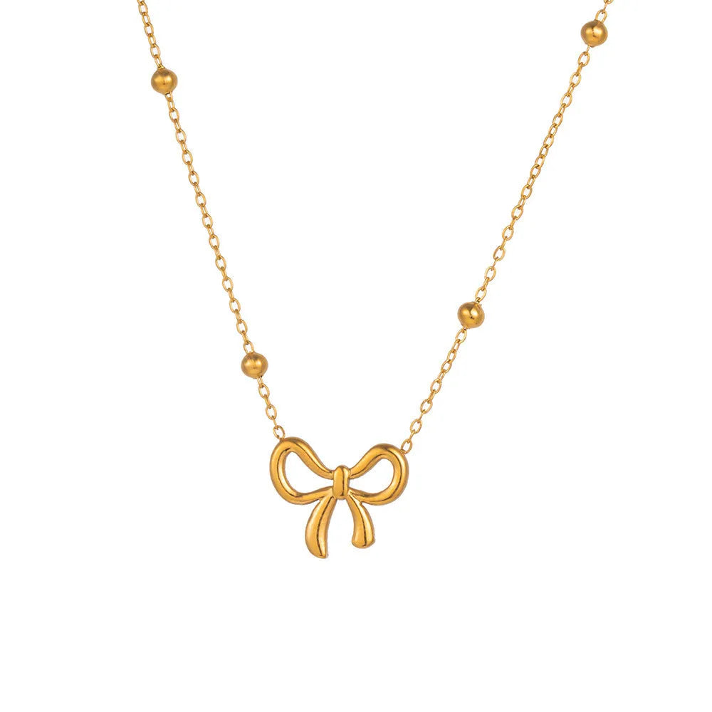 Gold titanium steel bow necklace with cross chain design on display