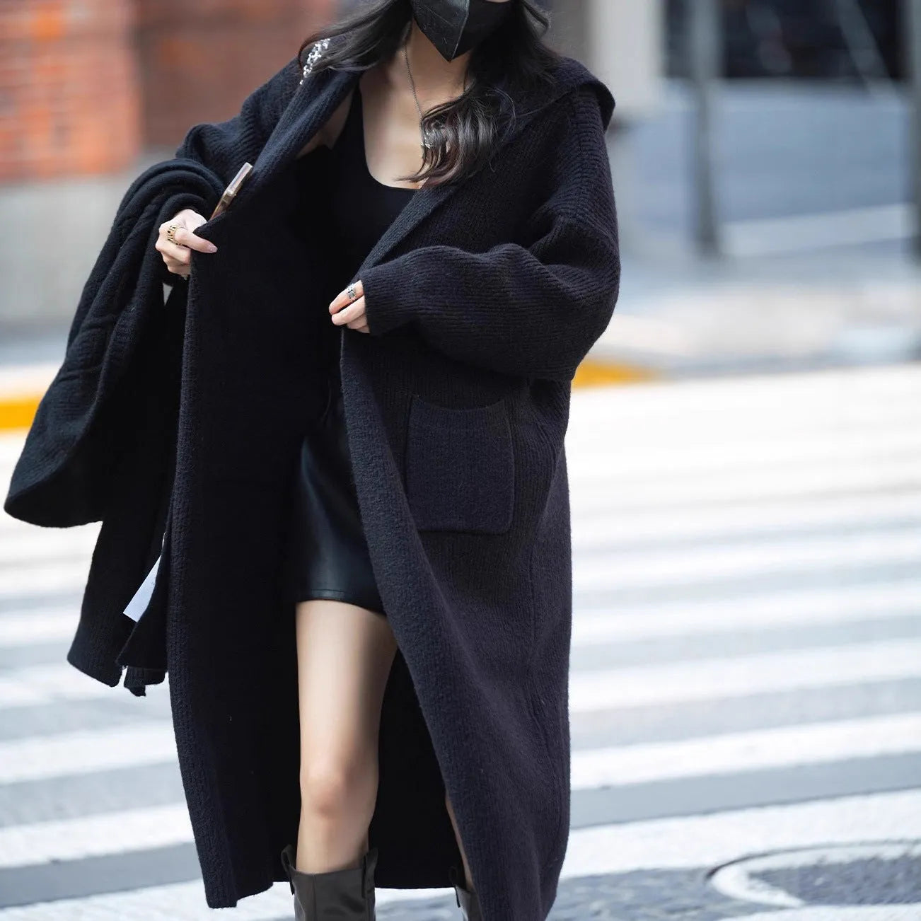 Long grey knitted cardigan coat with a hood and regular sleeves on a model.