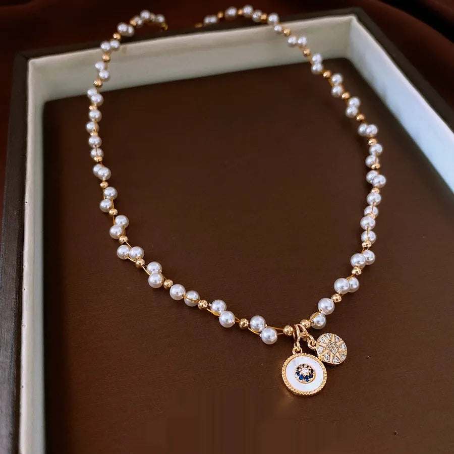Gold electroplated necklace with round imitation pearl pendant and zircon accents on clavicle-length chain