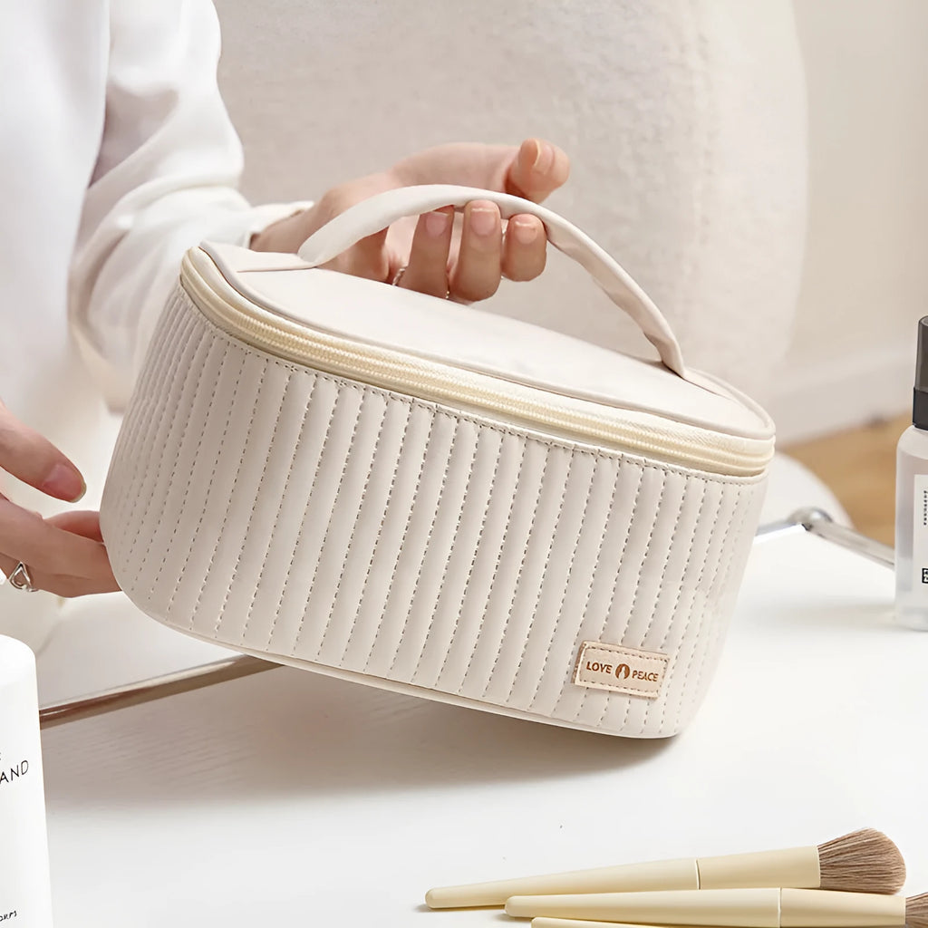Open-top cake style makeup bag in PU leather shown in a light colour, with cosmetics inside.