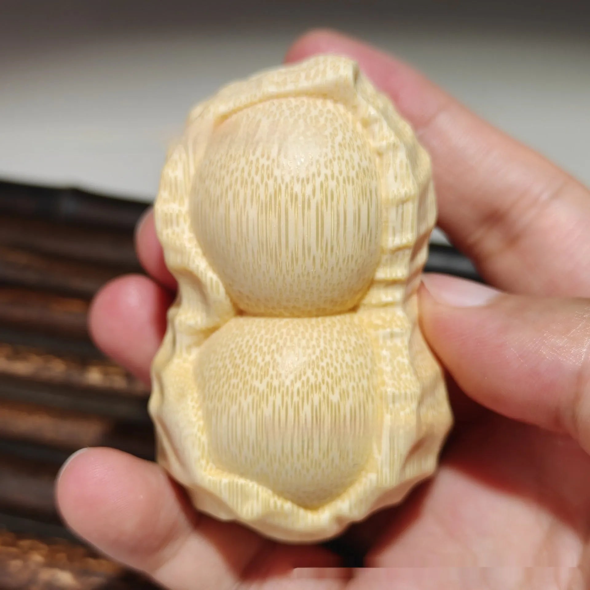 Solid natural bamboo ornament carved into a peanut shape on a wooden surface.