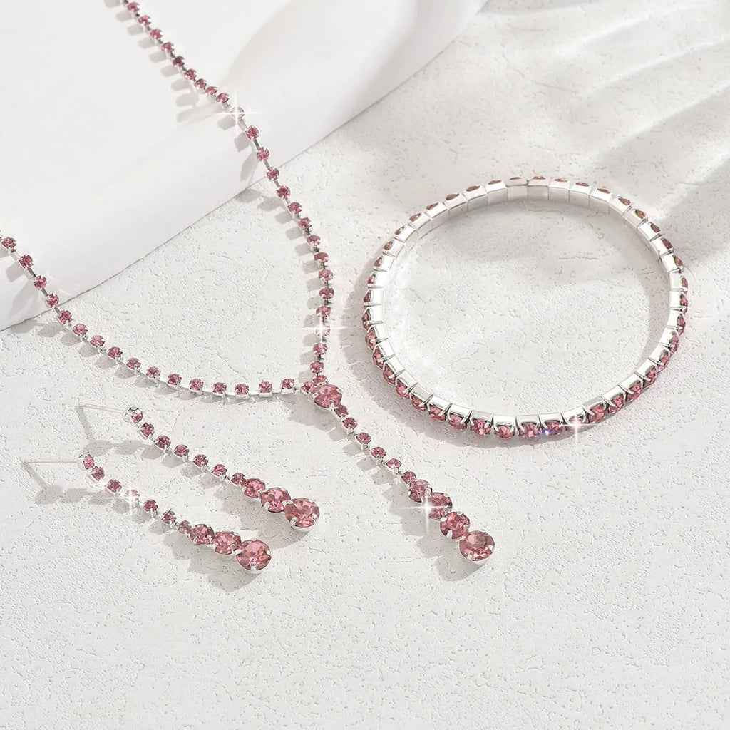 Rhinestone bridal jewellery set includes necklace, bracelet, and earrings in silver with tassel and heart elements