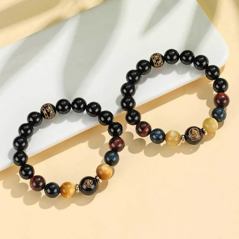 Black agate beaded bracelet with gold tiger eye accent and Chinese zodiac bodhisattva charm on neutral background