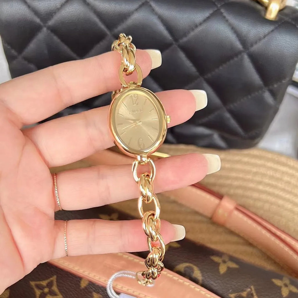 Lady's steel strap quartz watch with oval hollow chain in gold case gold face design