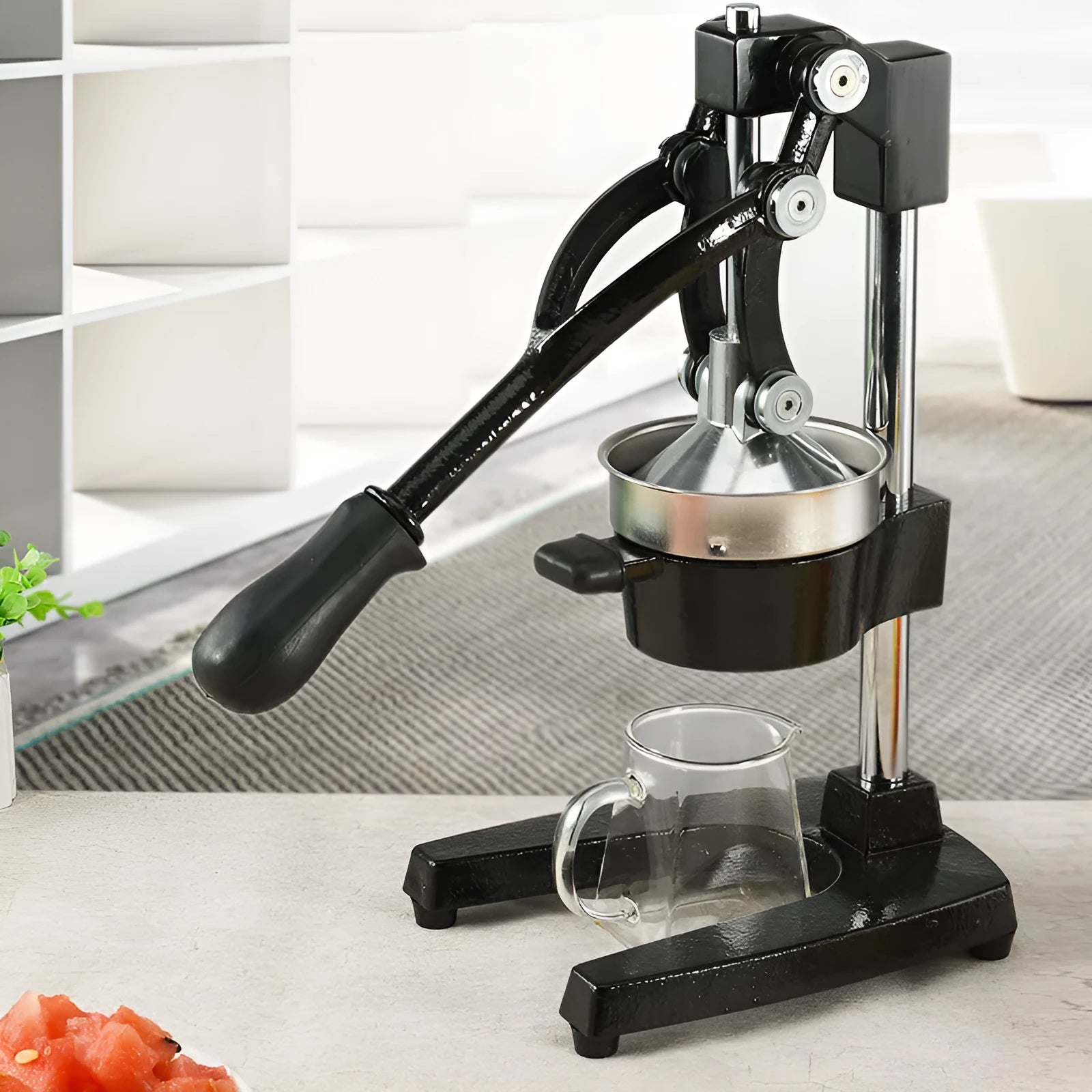 A black cast iron manual juicer with a stainless steel strainer, standing 40cm tall on a kitchen counter.
