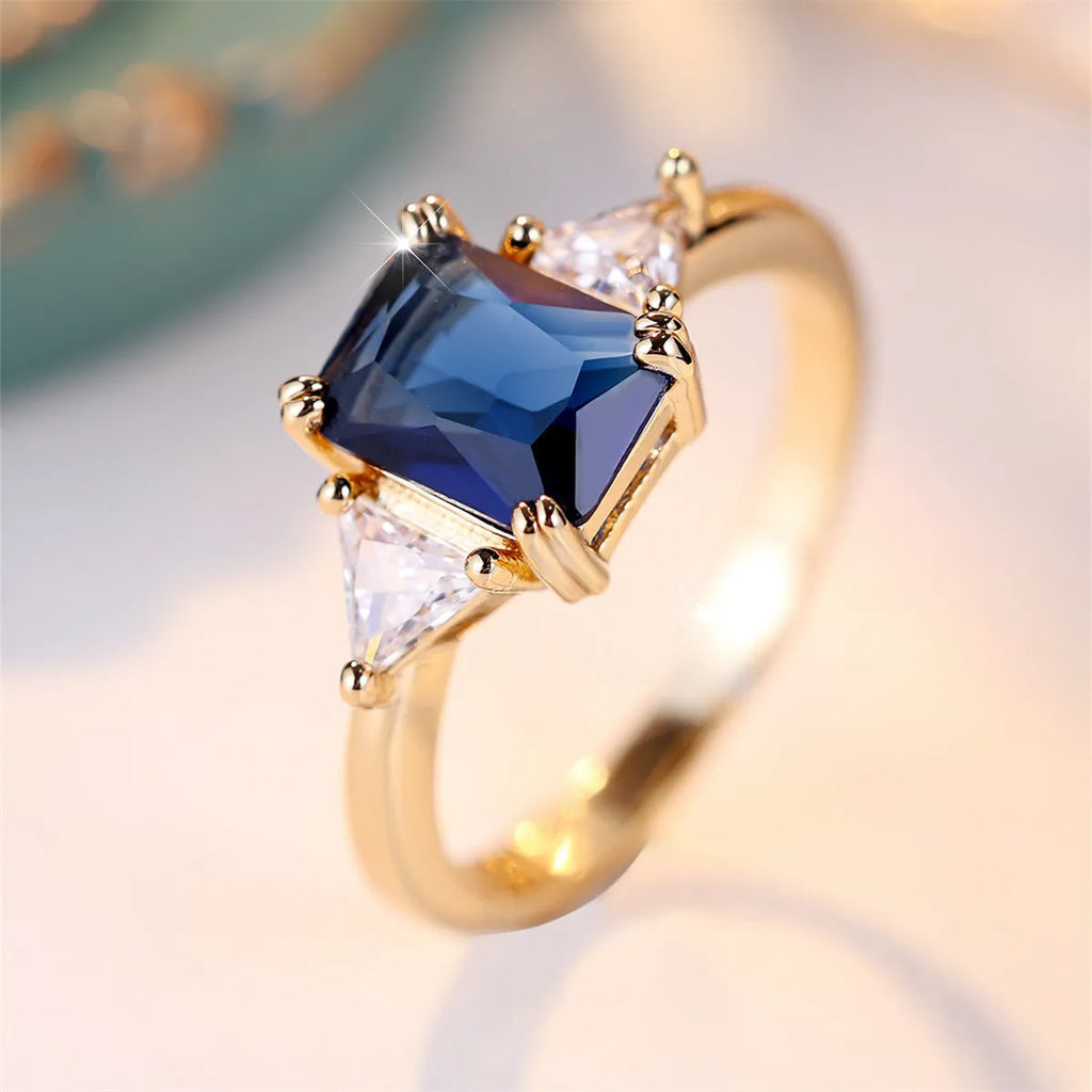 Gold sapphire blue rectangular copper ring for women on plain background