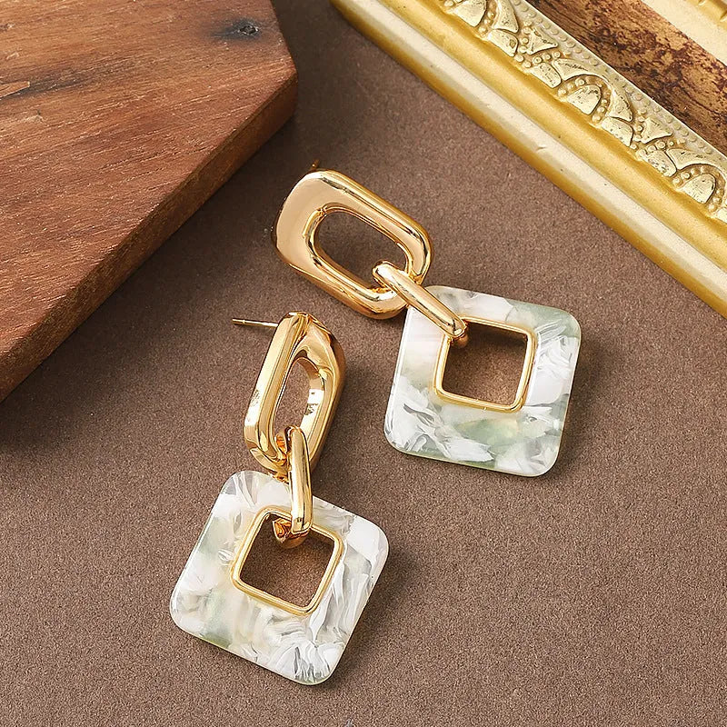 Dignified hollow geometric square copper earrings with electroplated finish on white background