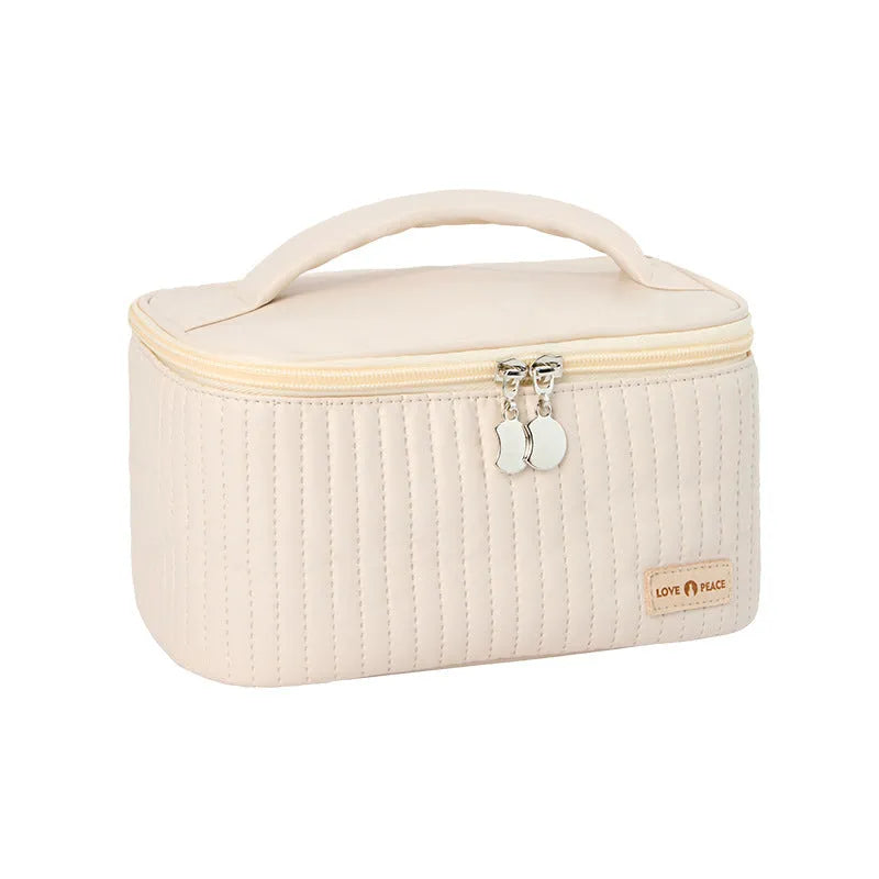 Open-top cake style makeup bag in PU leather shown in a light colour, with cosmetics inside.
