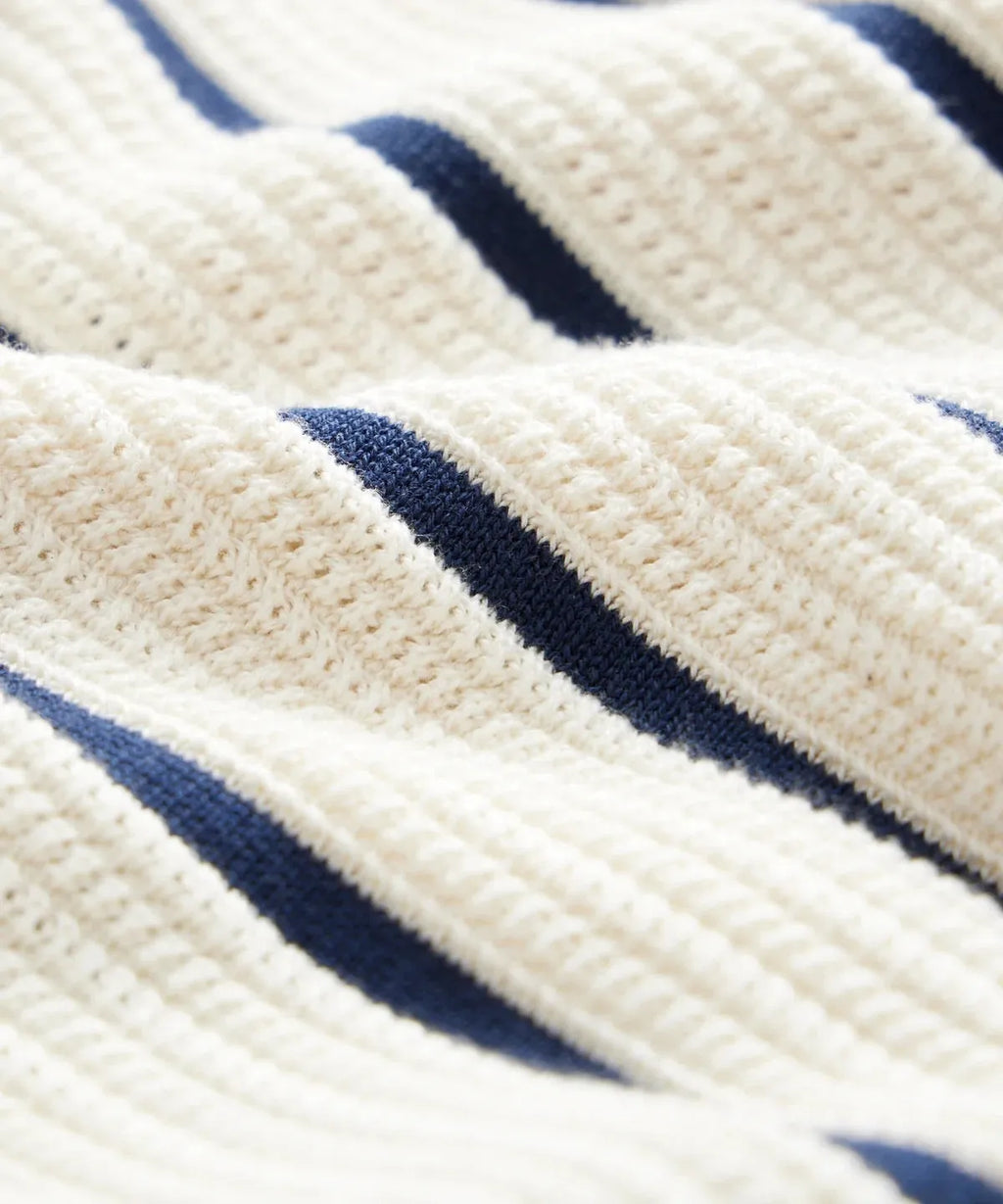 Men's white asymmetric short sleeve knitted top with a lapel, shown on a model.