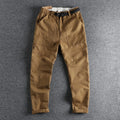 Men's khaki trousers with N buckle belt closure and zipper fly on a mid-waist fit.