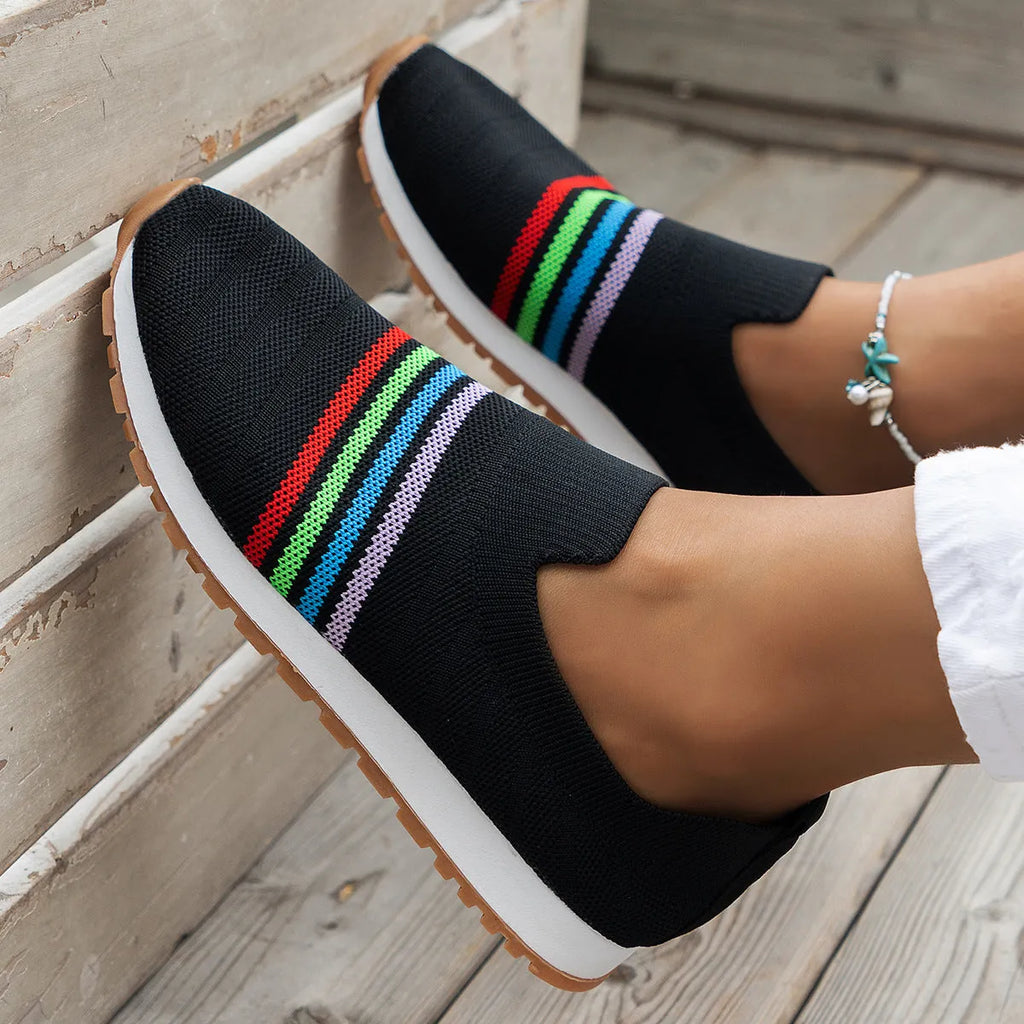 Women's casual flat sneaker pumps in beige with low wedge heel and round toe, side view on wooden floor