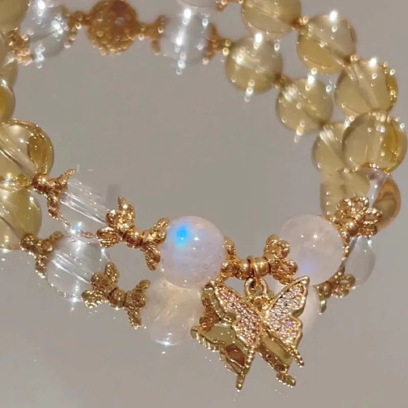 Moonstone white crystal beaded bracelet with citrine butterfly pendant on a white background