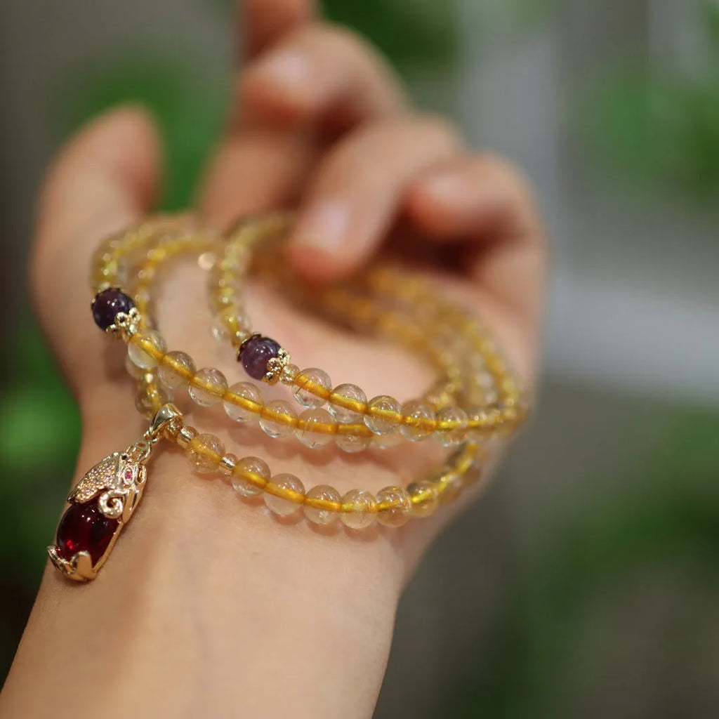Handmade gold and ruby quartz bracelet with a chopstick charm on a wrist.