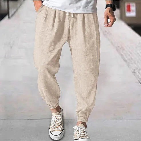 Men's loose cotton ankle banded trousers in khaki colour on a hanger.