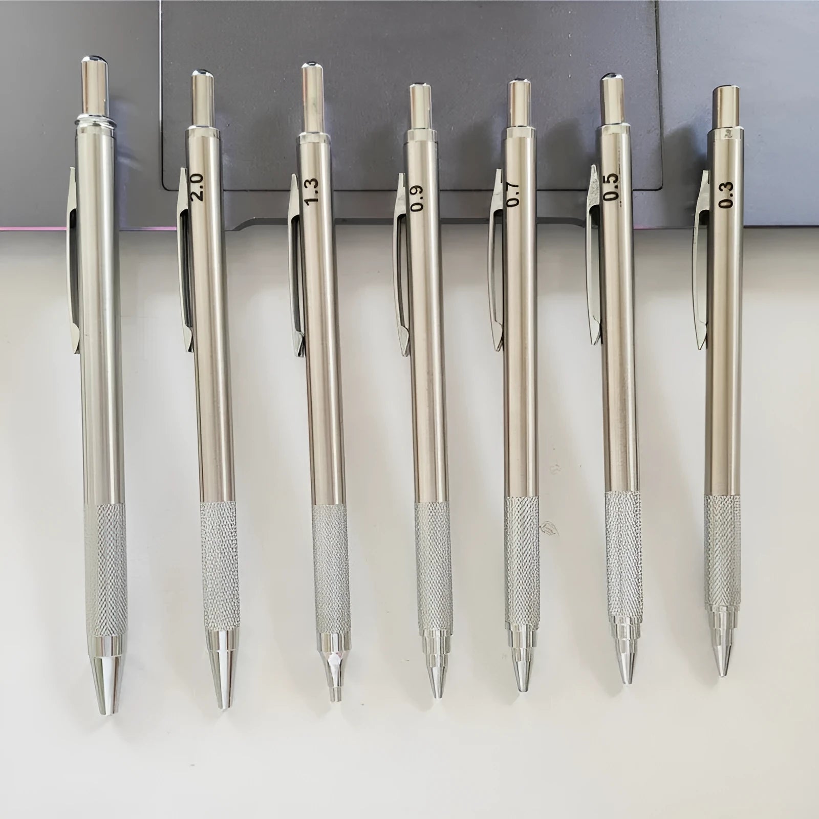 Silver metal automatic mechanical pencil with various lead size options shown.