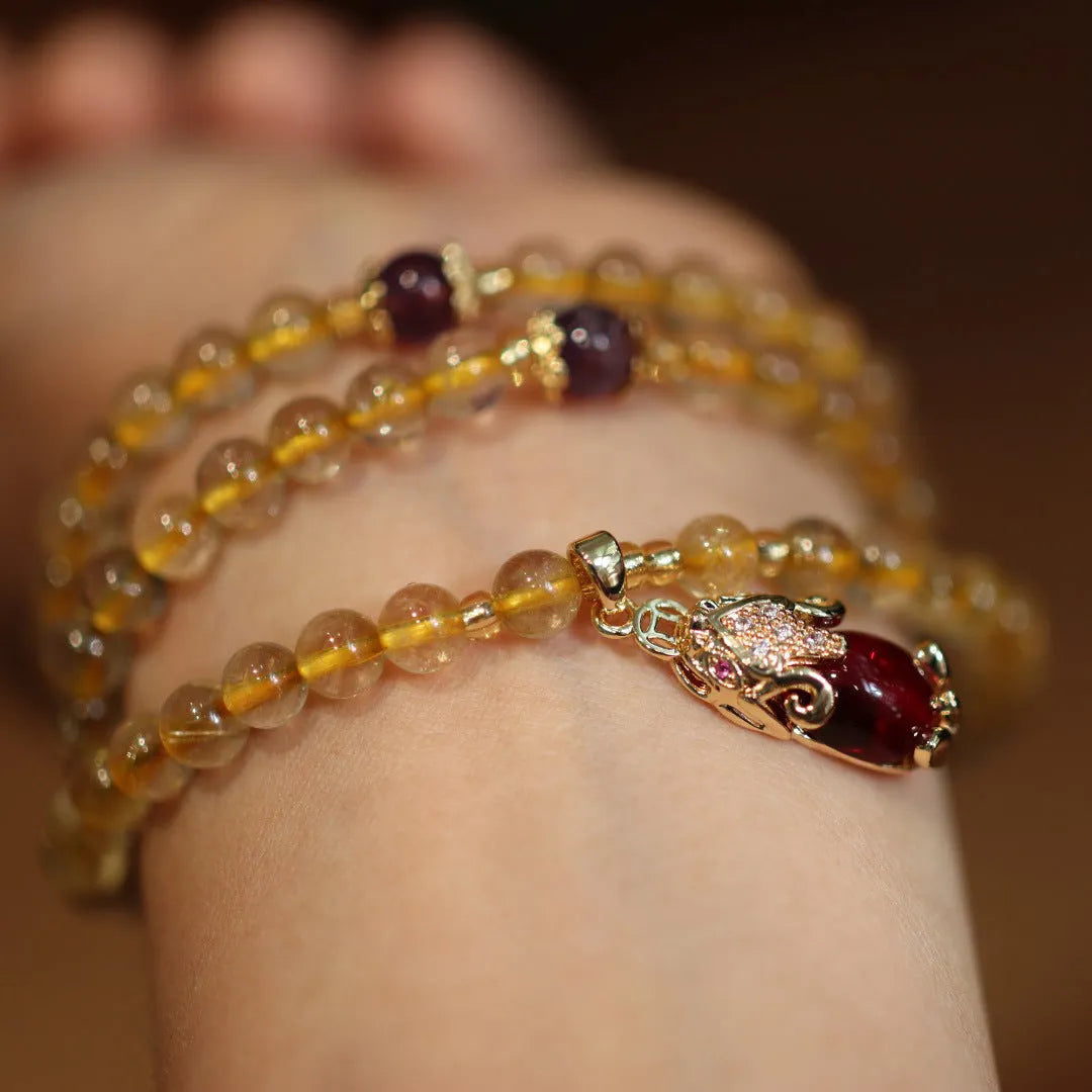 Handmade gold and ruby quartz bracelet with a chopstick charm on a wrist.