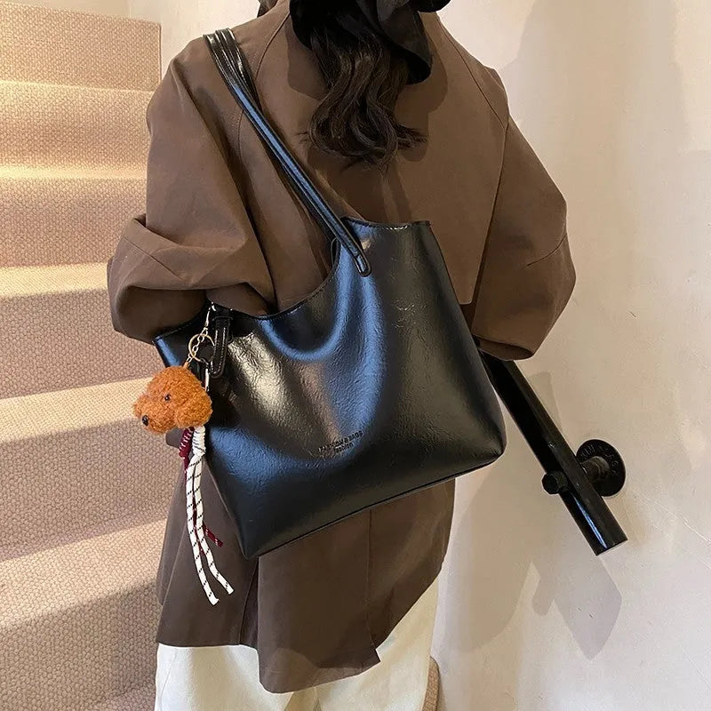 Women's PU commuter shoulder bag in black with stitching details and optional ribbon pendant, horizontal square shape