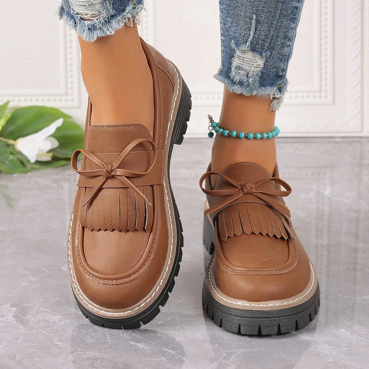 Black plus size women's loafers with a tassel and bowknot on a chunky rubber sole.