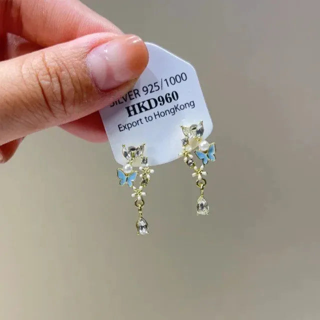 Close-up of women's geometric alloy earrings with rhinestones, a dangling tassel, and a heart detail.