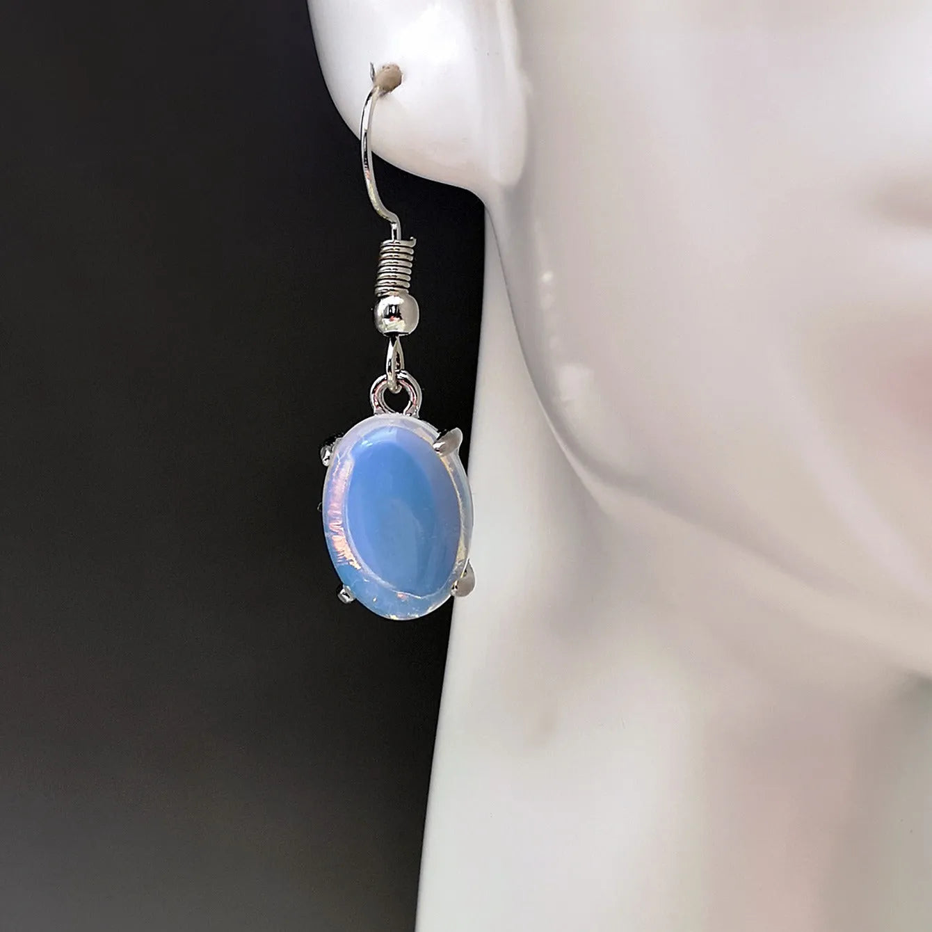 Pair of retro moonstone opal drop earrings with a cross design in moonlight white.