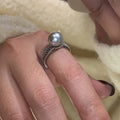 Geometric open copper ring with black pearl detail on a woman's index finger, showing adjustable opening.