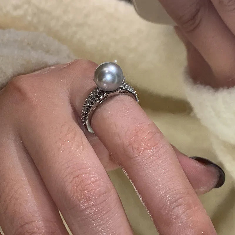 Geometric open copper ring with black pearl detail on a woman's index finger, showing adjustable opening.