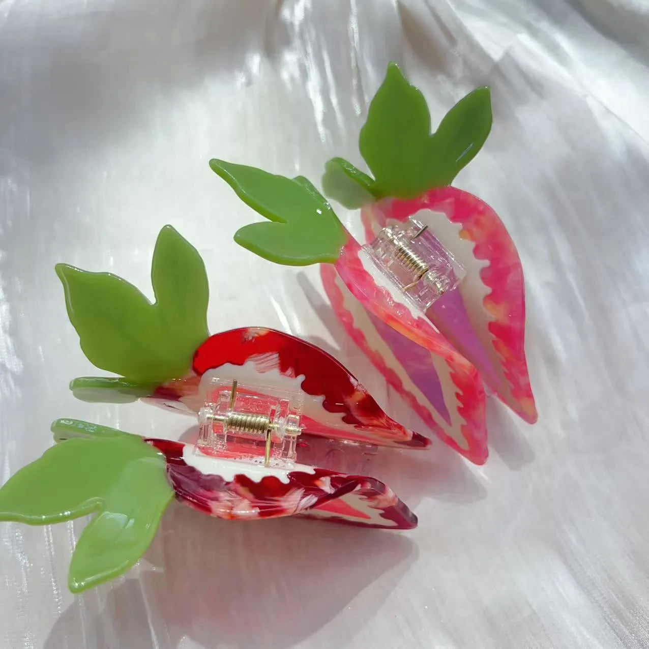 Close-up of a handmade strawberry hair clip in red or pink on a white background.