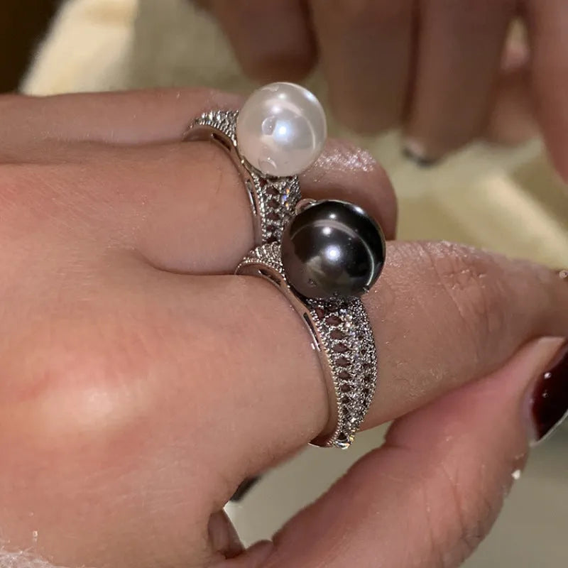 Geometric open copper ring with black pearl detail on a woman's index finger, showing adjustable opening.