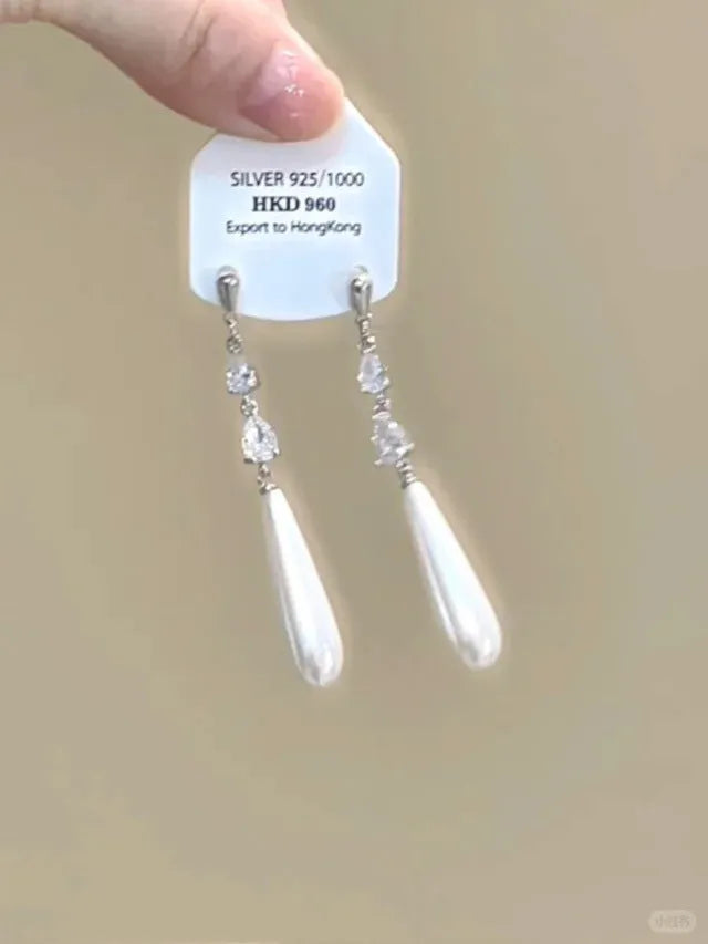 Close-up of women's geometric alloy earrings with rhinestones, a dangling tassel, and a heart detail.