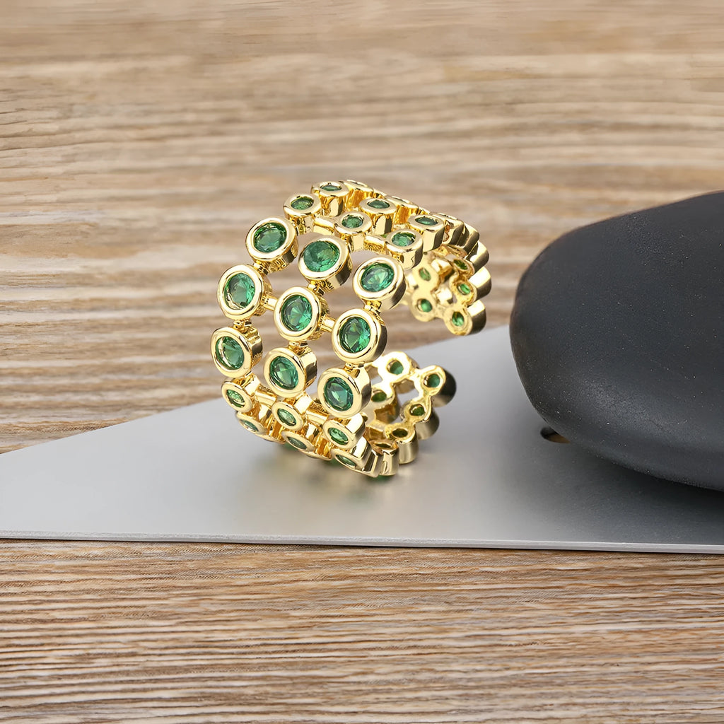 Gold coloured wide band ring with three layers of green zircons on a copper base plated with 18K real gold.