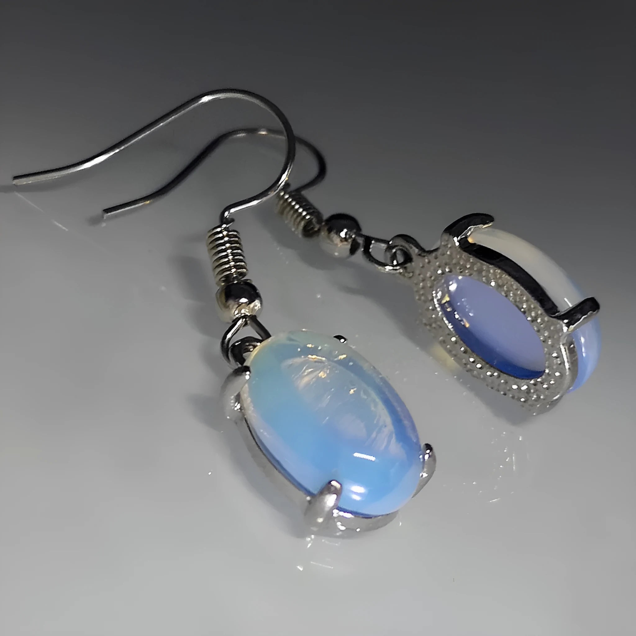 Pair of retro moonstone opal drop earrings with a cross design in moonlight white.