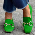 Green women's flat loafers with a round toe and metal buckle fastener on a rubber sole.