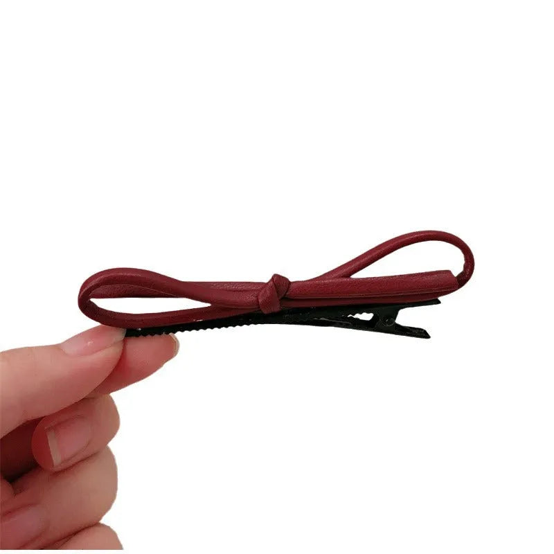 Wine red leather bow hair barrettes for women, showing front and side views