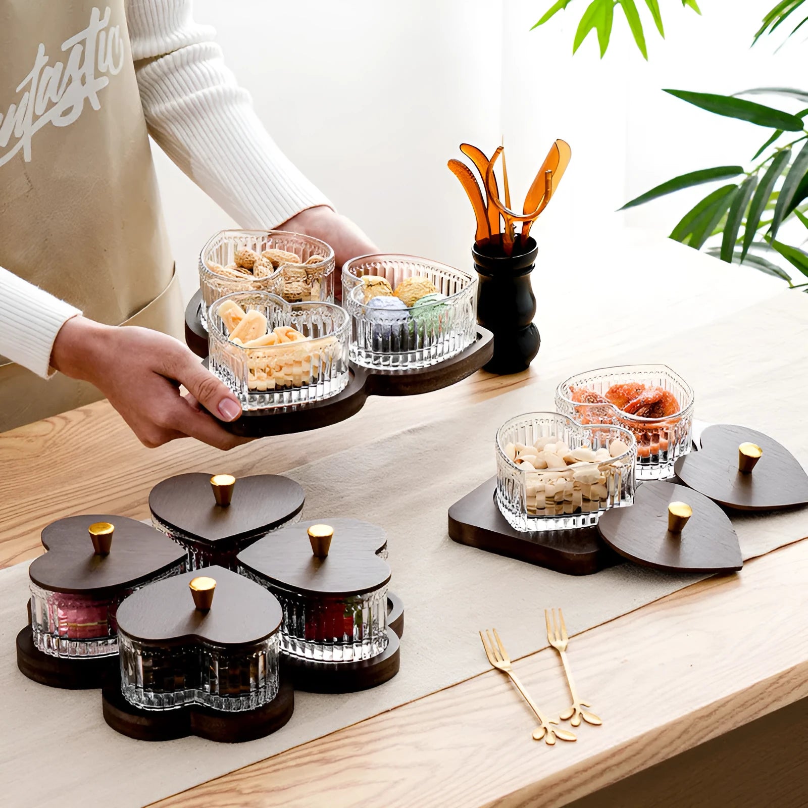 Glass foot bath fruit platter with coloured glaze and transparent heart-shaped lids on a multi-grid snack tray.