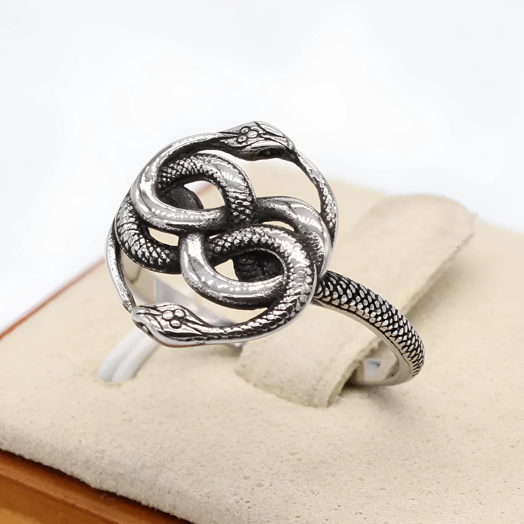Steel-coloured titanium steel ring with a detailed double snake design on a grey background.