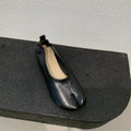 Women's black low heel pumps with chunky heel and round toe showing split toe horseshoe detail