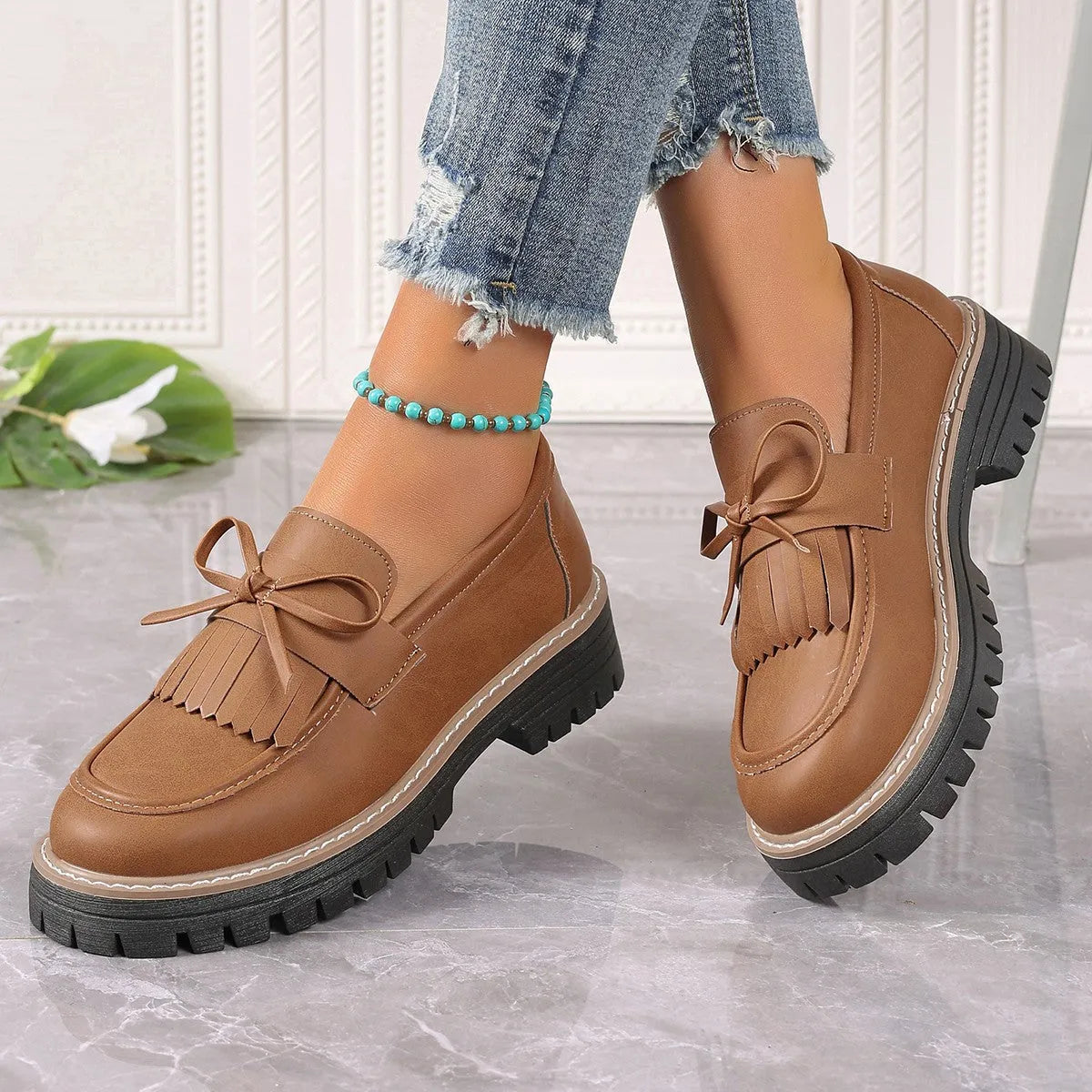 Black plus size women's loafers with a tassel and bowknot on a chunky rubber sole.