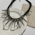 Leather necklace with winding tassel, round beads, and silver point rivet details.