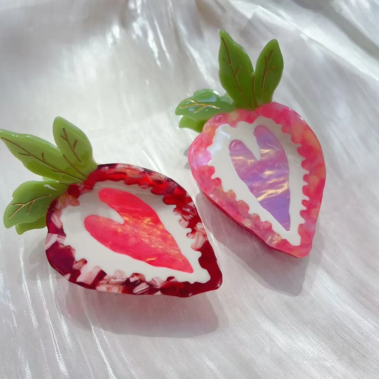 Close-up of a handmade strawberry hair clip in red or pink on a white background.